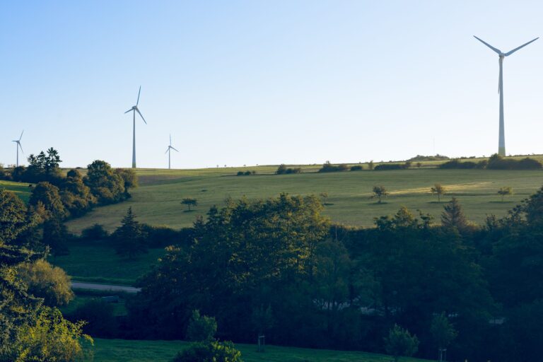 Scenic view of wind turbines on grassy hills in Luxembourg under clear blue sky.