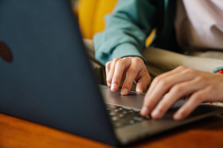 Crop unrecognizable distance employee surfing internet on netbook while working on project at desk in room